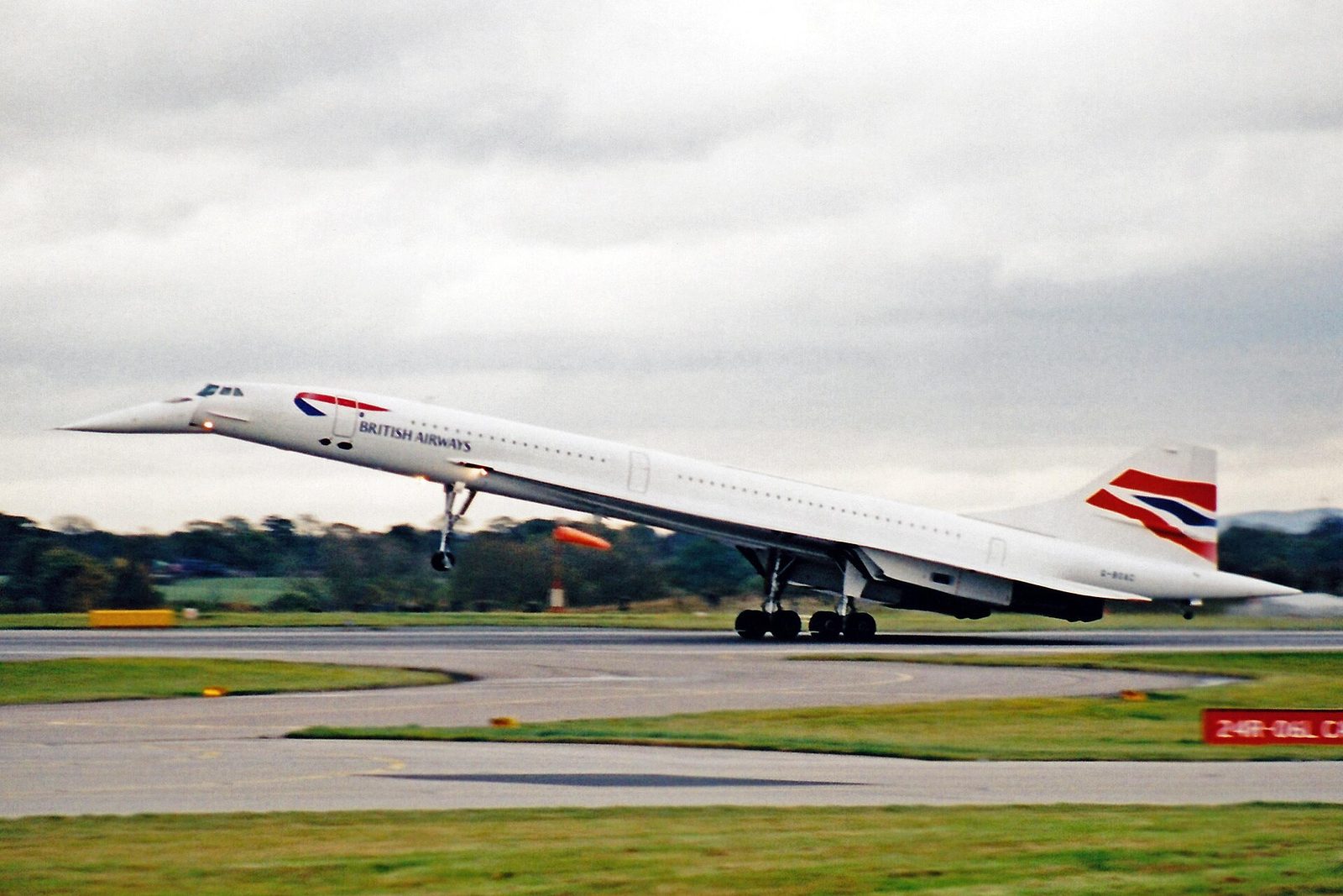 A British Airways Concorde low over the airfield with its landing gear down and nose drooped